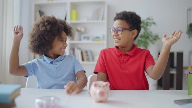 Brother and sister putting coins into piggybank, saving money for their dream