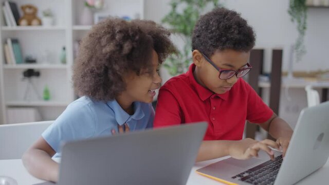 Cute African American brother and sister using laptops, children and technology