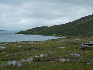 Lapland landscape at Virihaure lake with sami village Staloluokta houses and cottage, snow capped mountains and birch trees. Sweden summer moody and foggy wild nature, Padjelantaleden hiking trail.