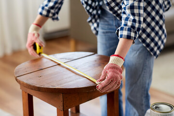 repair, diy and home improvement concept - close up of woman with ruler measuring old round wooden table for renovation