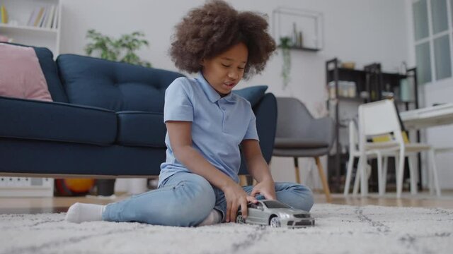 African American girl playing with a toy car at home, no to gender stereotyping