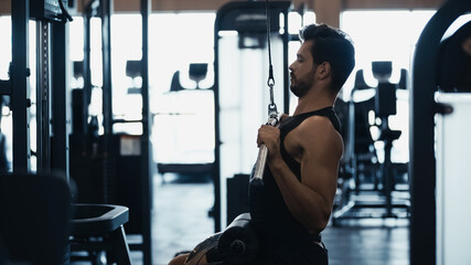 Fototapeta na wymiar side view of sportsman training on fitness machine in gym.