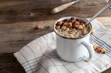 Porridge with hazelnuts in a enamel cup with spoon