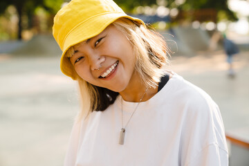 Asian girl wearing hat looking and smiling at camera