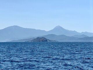An uninhabited island in the Mediterranean. Islands surrounded by the sea, a quiet harbor for yachts. Seashore against the backdrop of mountains and clear sea.
