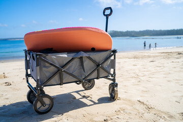 Outdoor beach cart wagon on a sandy beach near the ocean. Family vacation holidays