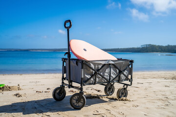 Outdoor beach cart wagon on a sandy beach near the ocean. Family vacation holidays - obrazy, fototapety, plakaty