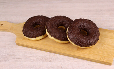 Round donuts in chocolate on a wooden cutting board
