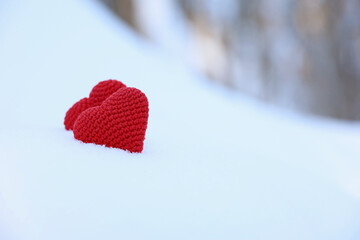 Love hearts, Valentine's card, two red knitted symbols of passion in the snow forest. Background for romantic event, celebration or winter weather