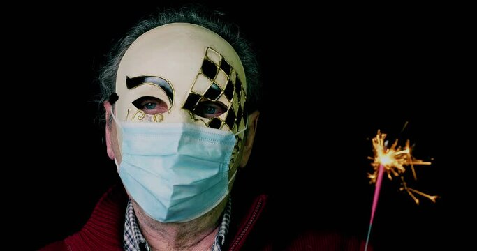 Uomo con maschera di carnevale e mascherina per il Covid-!9 che tiene in mano una scintillante stellina