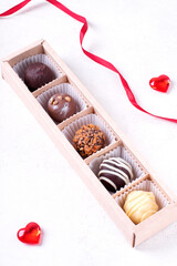 Assorted chocolate sweets in the gift box on the white table. Valentines day dessert. Confectionery variation