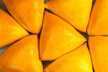 Homemade baked triangular buns lie on white parchment.
