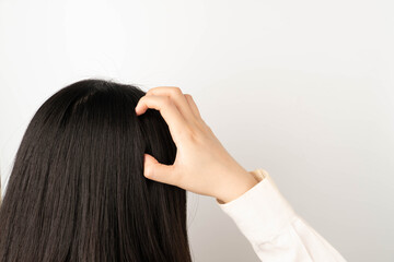 Woman scratching her head because of an itchy scalp. Causes of itchy includes dandruff, seborrheic...