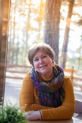 Mature woman 60s years old is lunching with coffee in cafe.