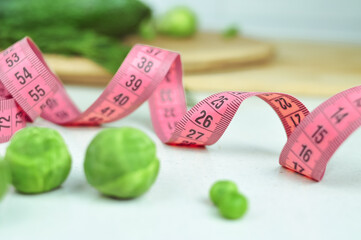 Pink tape measure and green vegetables diet concept