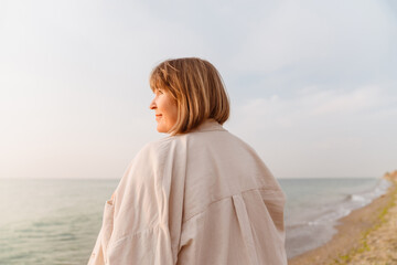 Obraz premium Senior european woman smiling while walking on beach