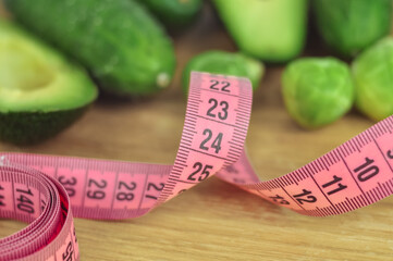 Pink tape measure and green vegetables diet concept