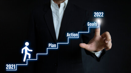 Fototapeta na wymiar Businessman pointing to the growing plan of successful business in 2022 year and a figure climbs the ladder of success. Year 2022 plan, action and goals.