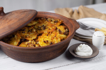 Potato pancakes with fried onions and sour cream in a ceramic pan
