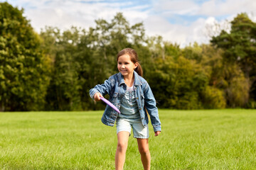 childhood, leisure and people concept - happy girl playing game with flying disc at park