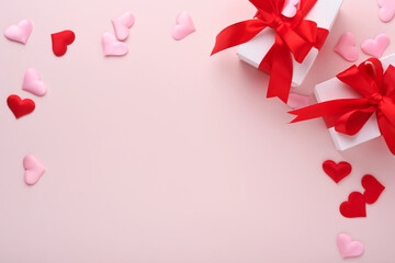 White gift boxes with red ribbon and small red decorative hearts on pink background. Top view with copy space. Valentines day or Wedding romantic concept. Festive composition. Mock up.