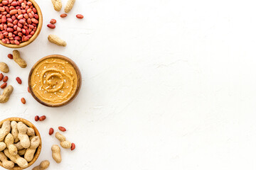 Creamy peanut butter and nuts in wooden bowls, top view