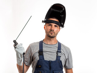 A man with a welding mask on his head, raised up, open face, holding welding wires and an electrode...