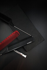 two combs with a metal handle, a red plastic comb and a shiny hairpin dissolve on a black background