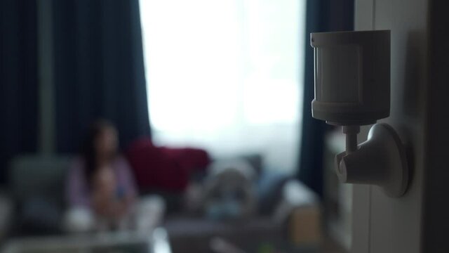 Smart home wireless motion sensor installed on the wall of the living room, motion detector used to detect activities like movement and control smart lights. High quality 4k footage