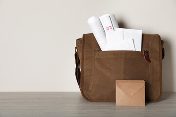 Postman's bag full of letters and newspapers on wooden background. Space for text