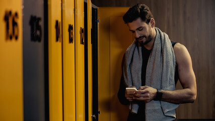 happy sportsman messaging on smartphone in locker room.