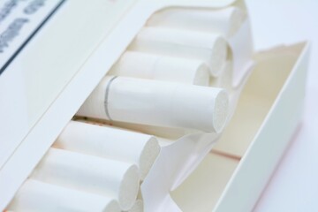 A closeup of an open white pack of cigarettes on a white background.