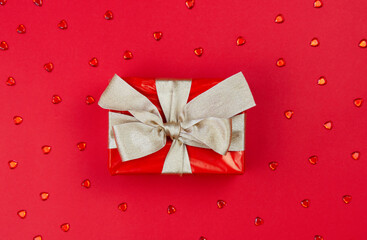 The concept of celebrating different holidays. Gift box with a golden bow on a red background.