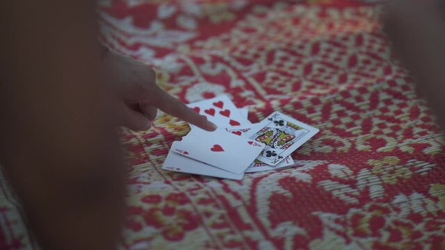 Playing Vietnamese card game tien lien 13 on bamboo mat with winning ace pair