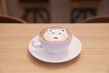 Cute bear latte hot coffee in white cup on wood table, read to serve.