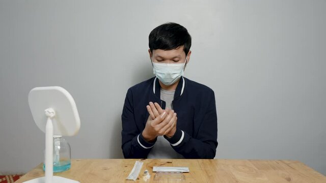4K, Asian man washing his hands with alcohol gel before taking the test. Rapid antigen test kit to test yourself for COVID-19 epidemic at home