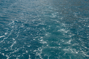 Bubbling water and sea foam from the motor of the boat, concept of water movement, gravel sea color.