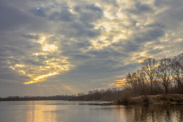 spring landscape. sun shining through heavy clouds over the lake