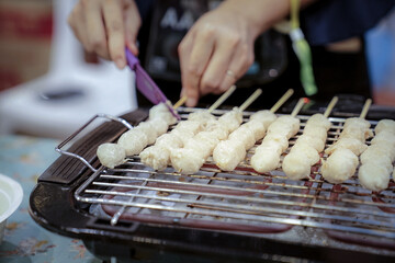 woman hand slide meat ball that was grilled on the grilling machine.