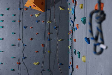 Wall with holds and climbing ropes in gym