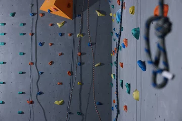 Fotobehang Wall with holds and climbing ropes in gym © New Africa