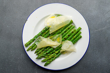 Asparagus grill on plate with parmesan on grey concrete table top view