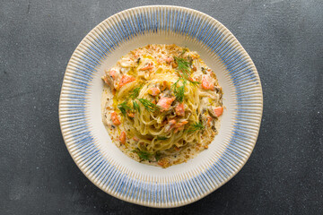 tagliatelli pasta with salmon and creamy sauce on grey concrete table top view