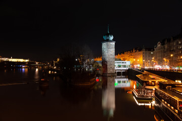 Obraz premium Prague at night, boat on the dock of the Vltava river, reflection of lights