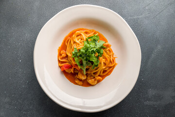 Pasta spaghetti with shrimps and tomato sauce on grey concrete table top view