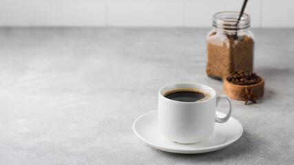  Black instant coffee in a white mug on a gray background. Copy space.