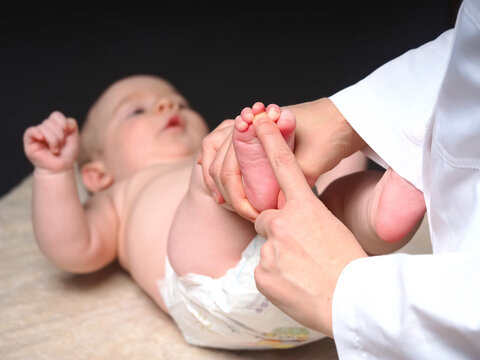doctor checks the reflexes of a newborn baby on the sole of the foot