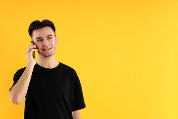 Young man talk on phone on yellow background