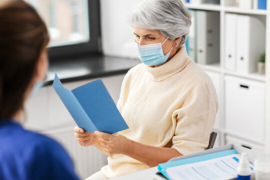 Medicine, Health And Vaccination Concept - Doctor Or Nurse And Senior Woman Reading Medical Brochure At Hospital