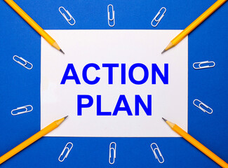 On a blue background, white paper clips, yellow pencils and a white sheet of paper with the text ACTION PLAN